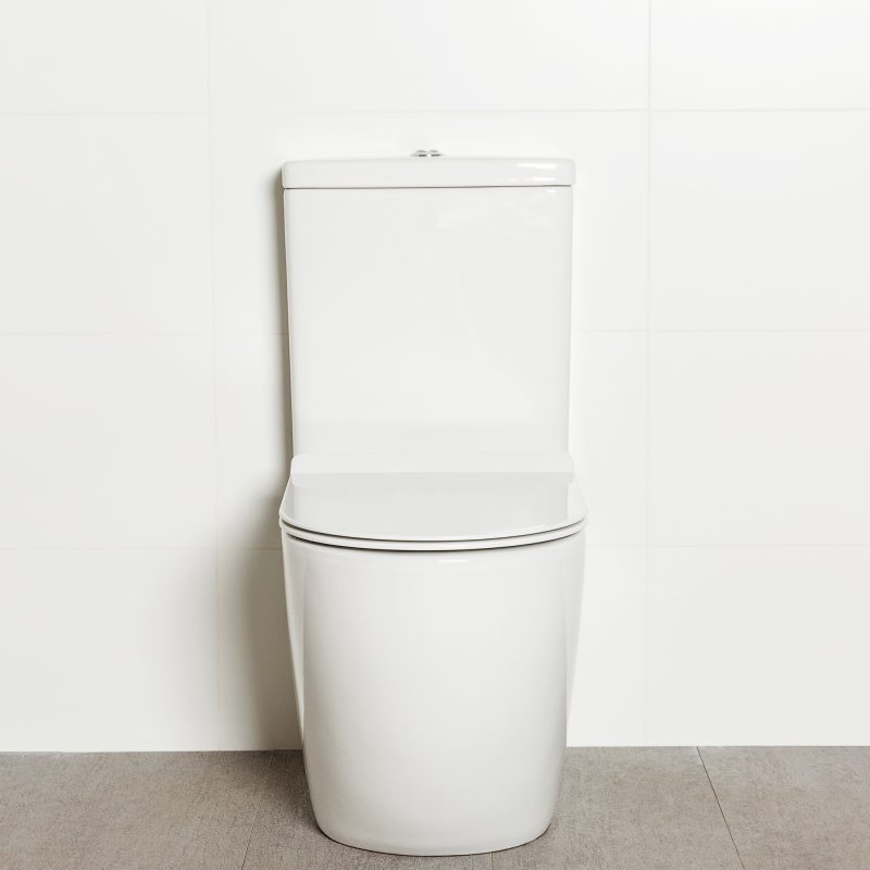 Milu Odourless Crest back-to-wall toilet front view with toilet seat down. Positioned against white tiled wall on warm grey coloured floor tiles