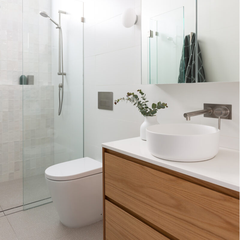 Milu Mod in-wall odourless toilet in an ensuite with timber vanity and white and beige hand cut ceramic tiles